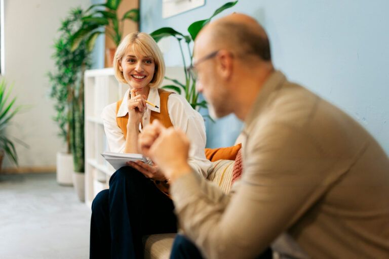 Female therapist smiling while listening to a male patient in a bright office